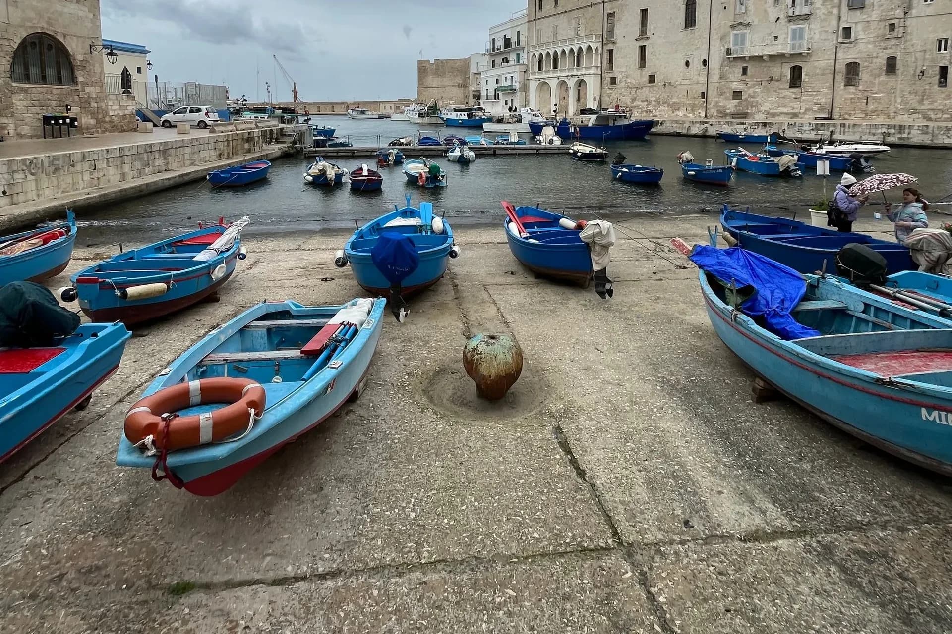 Fishing boats beside historic stone waterfront buildings in Italy