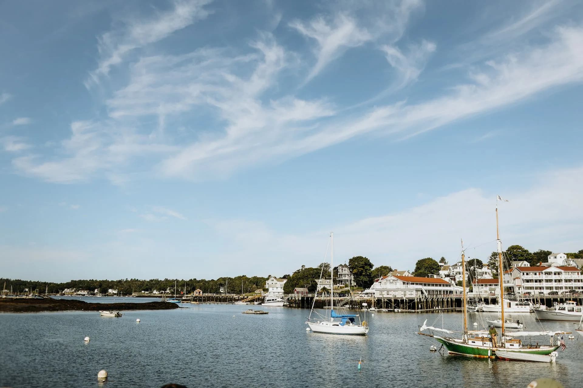 Sailboats and a harbor town beneath a blue sky in Maine, United States