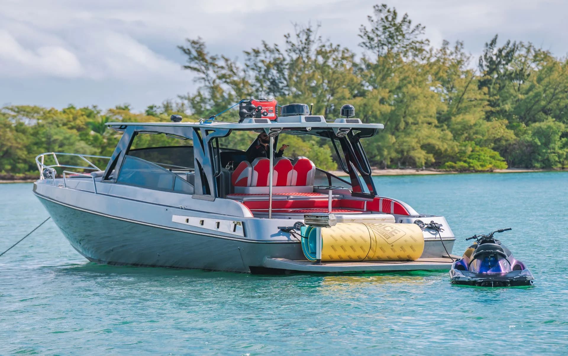 A motorboat with an inflatable towable beside green riverbanks.