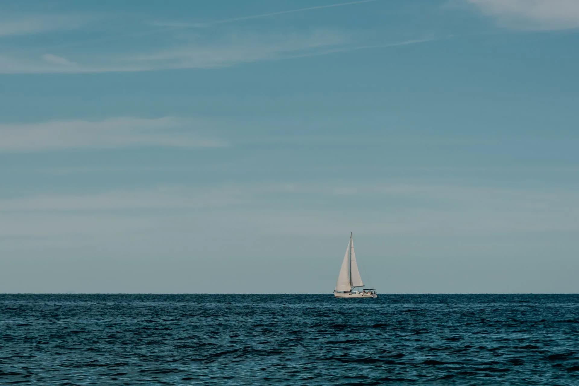 A sailboat under a broad blue sky.