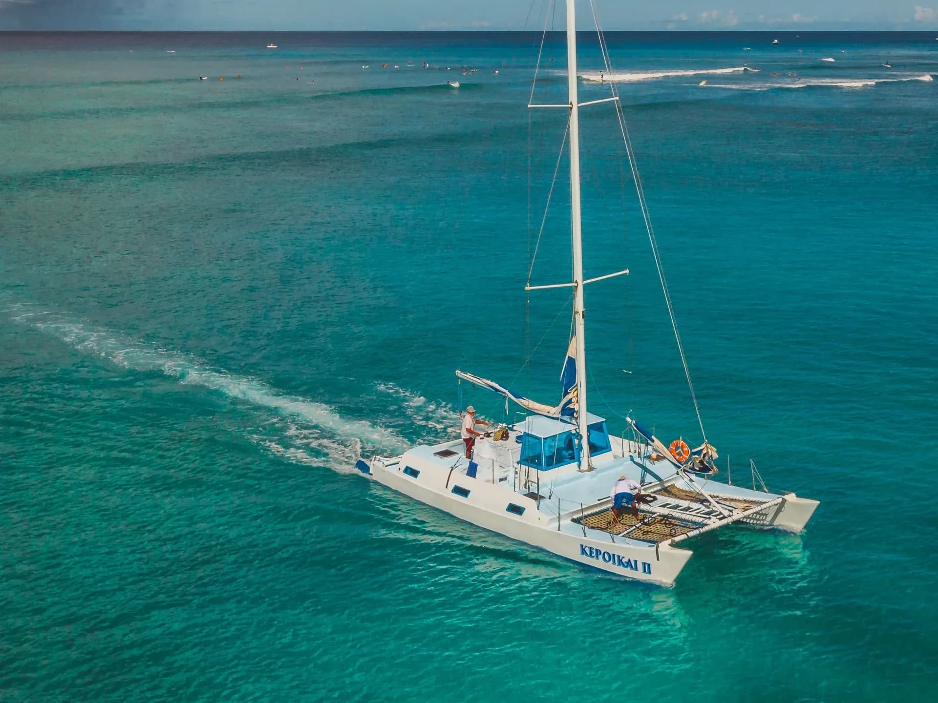 A catamaran sailing over clear blue water.