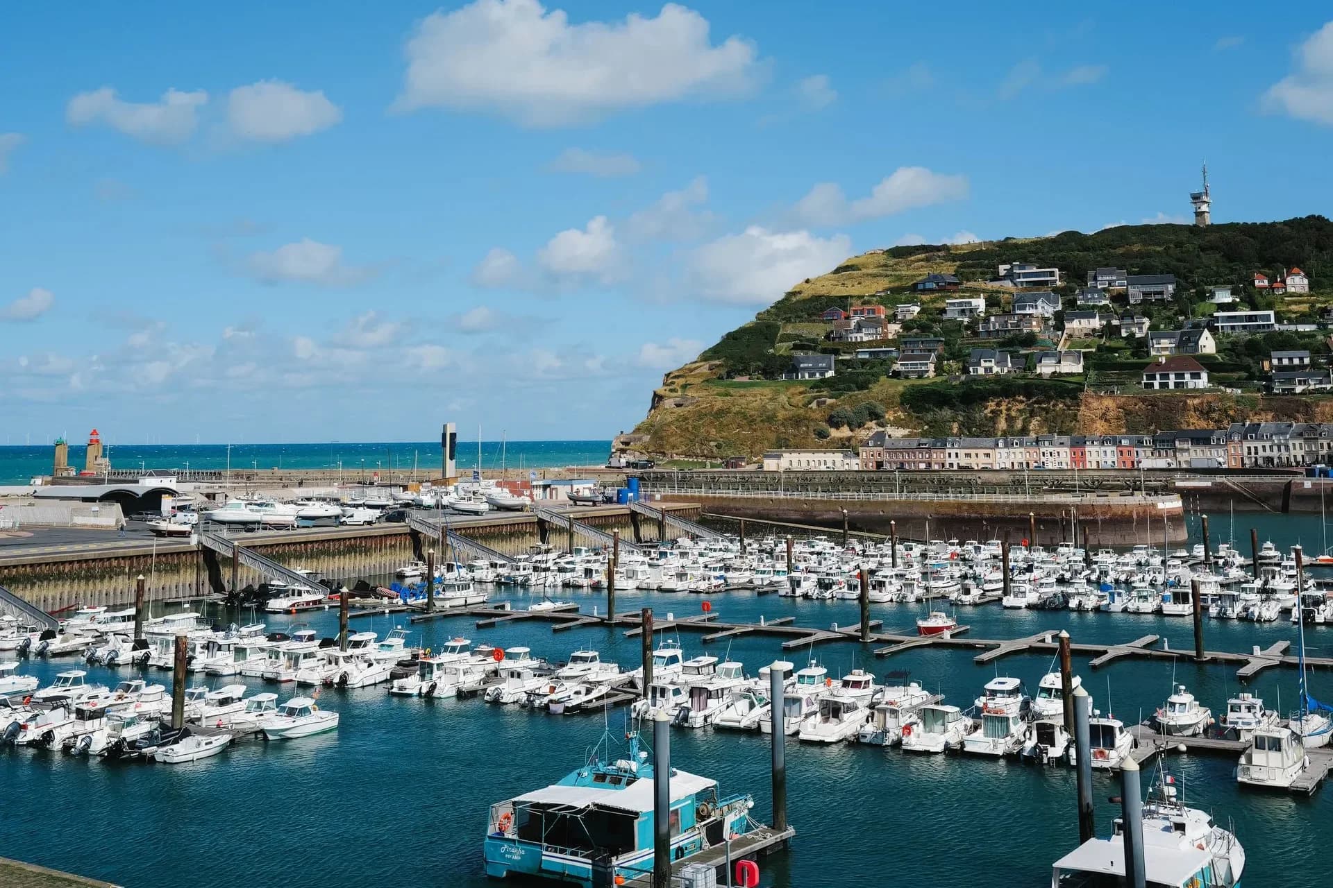Yachts in a coastal marina below a hillside at Fécamp, France
