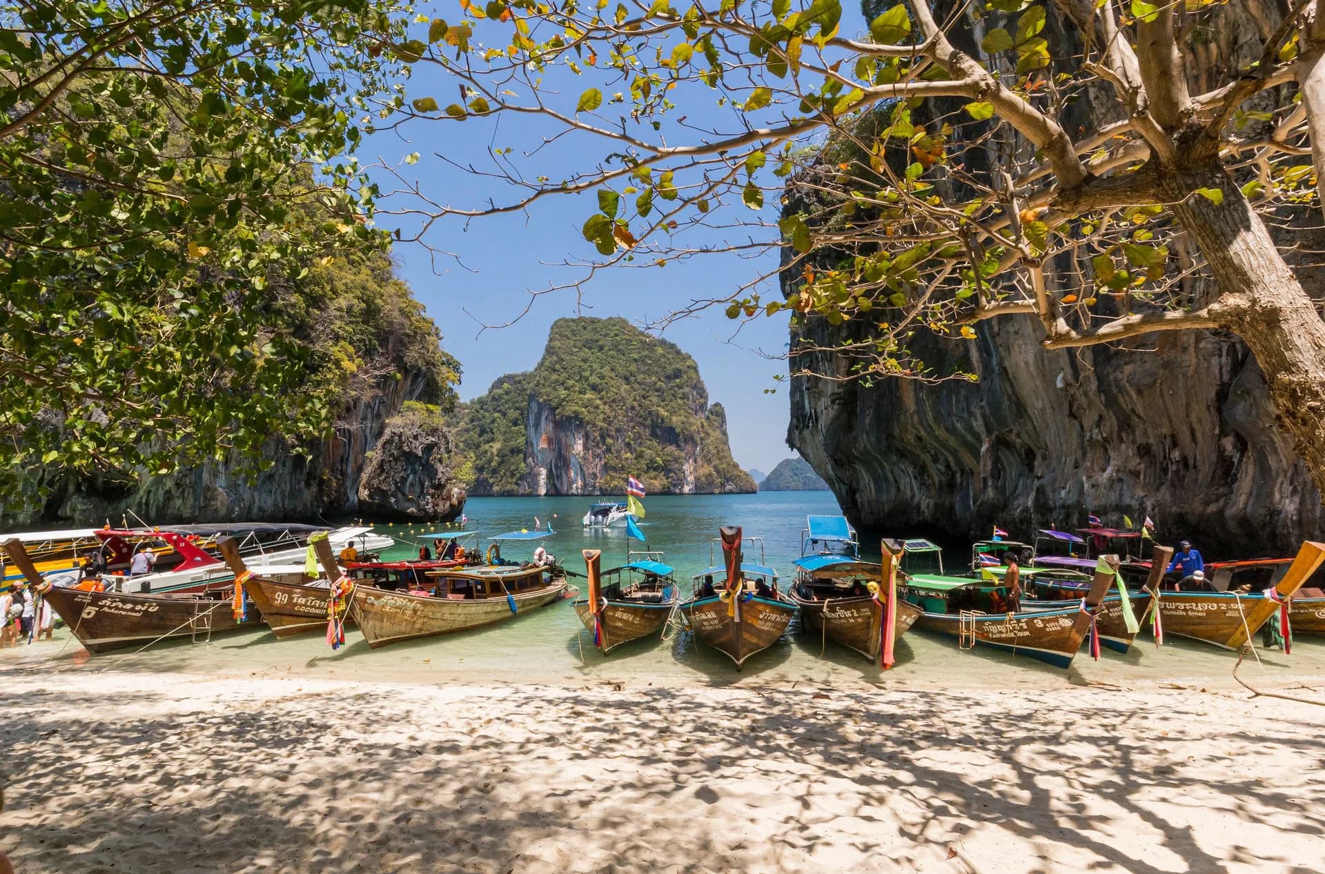 Boats by a sandy beach and limestone formations in Krabi, Thailand