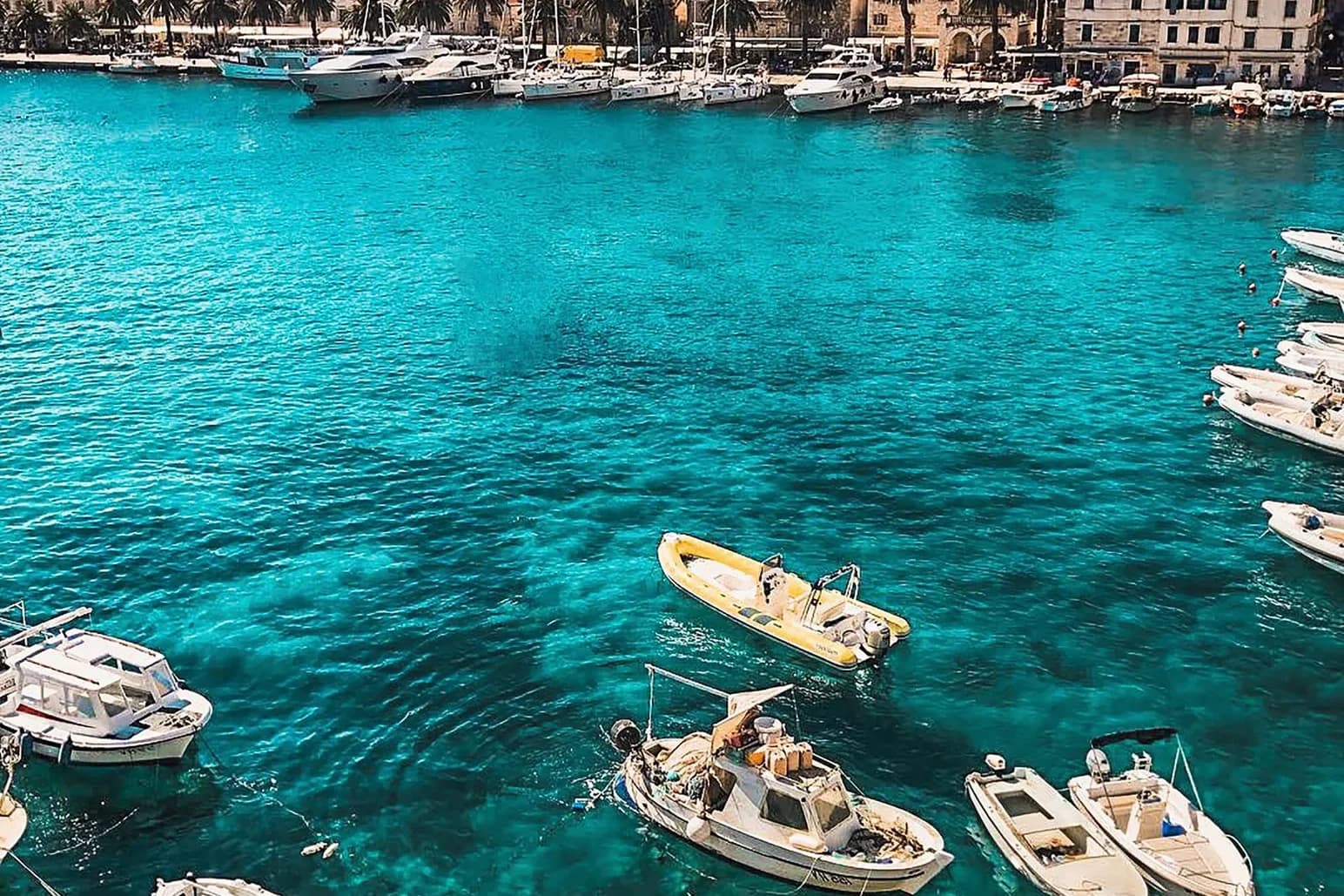 Boats in turquoise harbor water in Hvar, Croatia