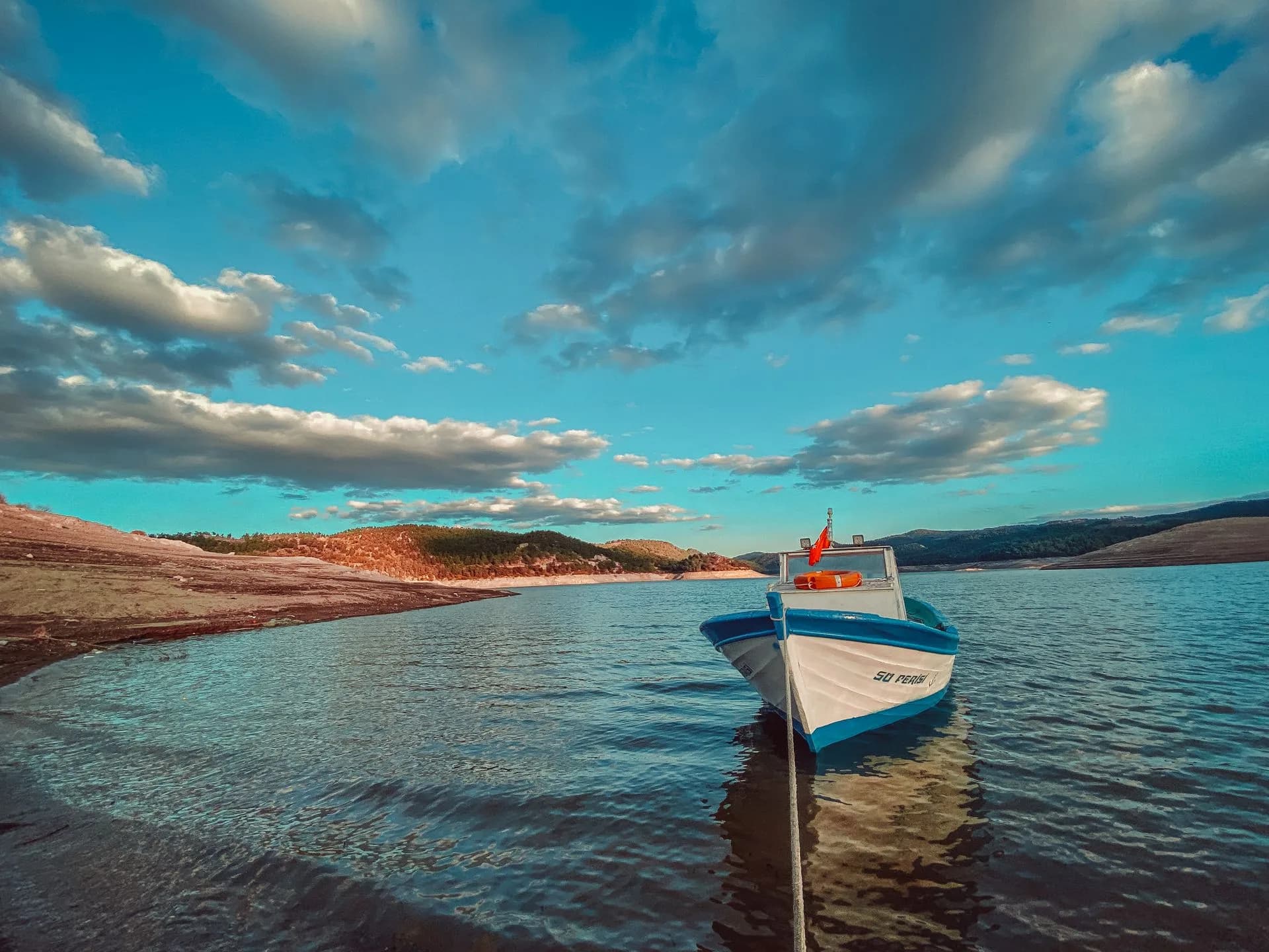 A white motorboat on a lake beneath a cloud-filled sky.