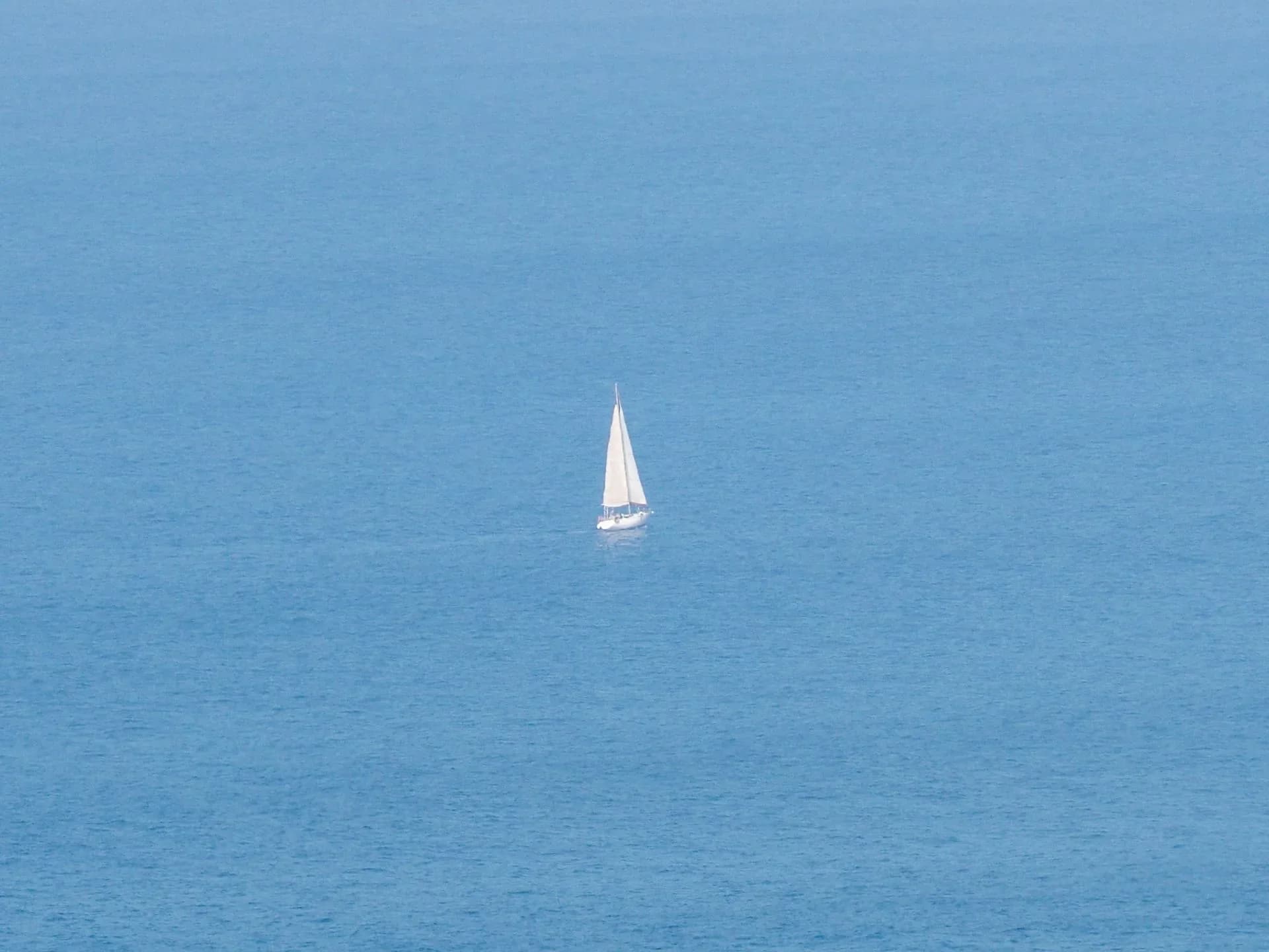Aerial view of a sailboat surrounded by blue water.