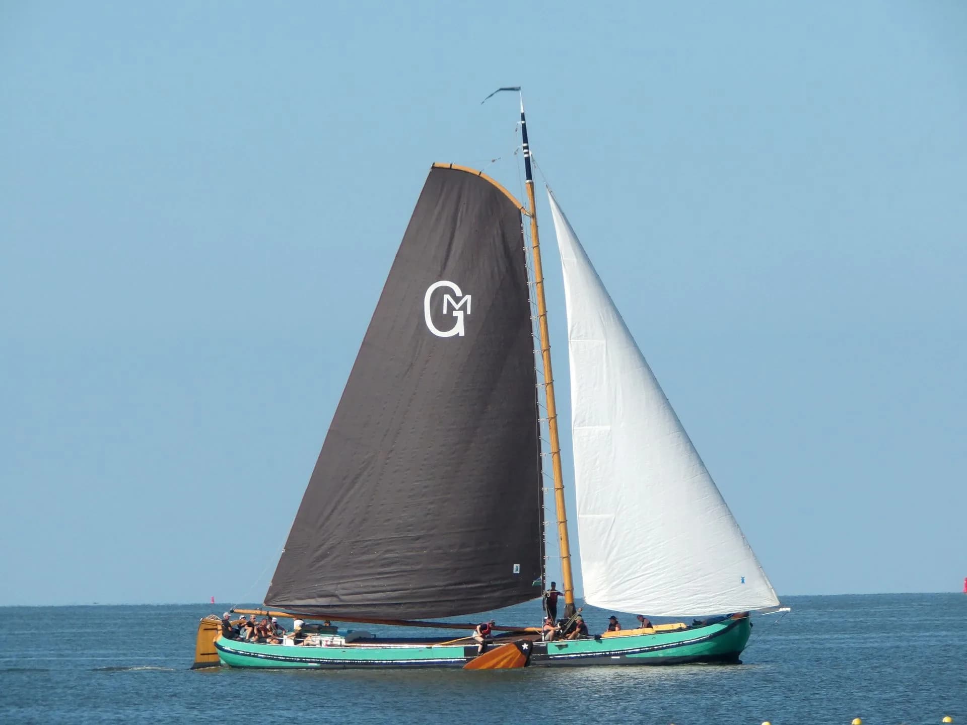 A sailboat carrying black and white sails on open water.