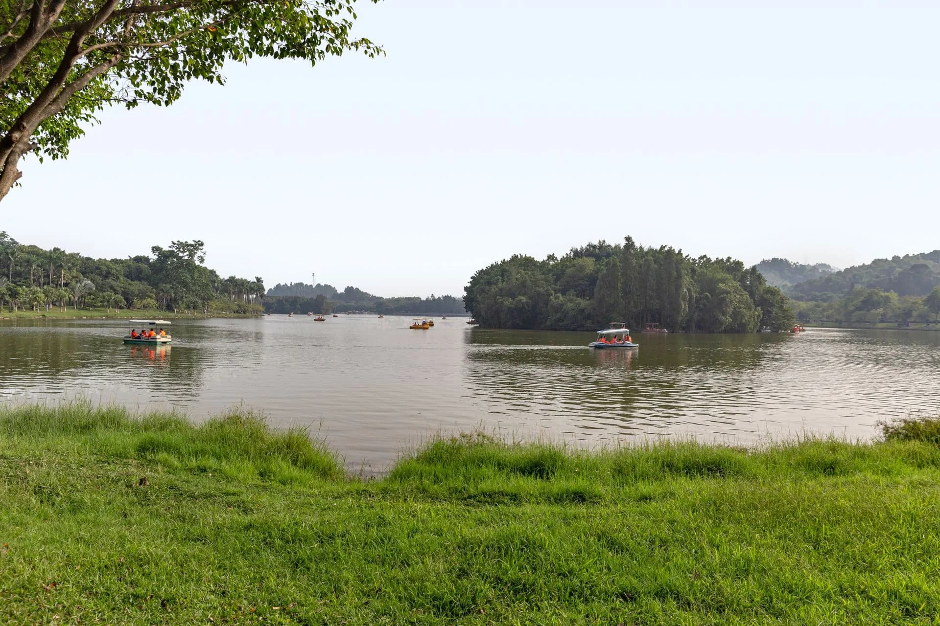 Small boats on a calm lake surrounded by greenery.