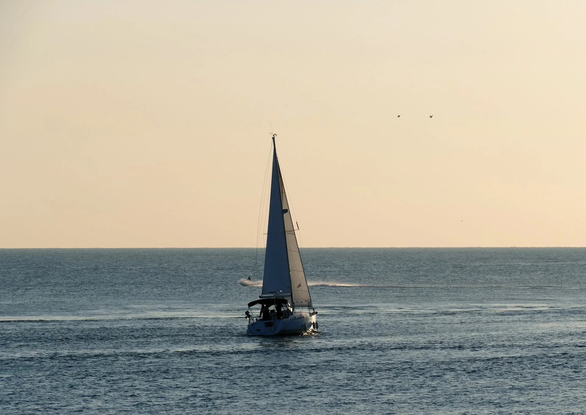 A sailboat silhouetted on the water at sunset.