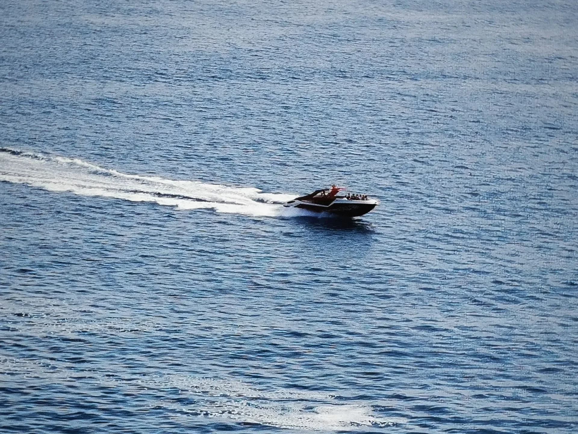 Aerial view of a motorboat speeding over blue water.