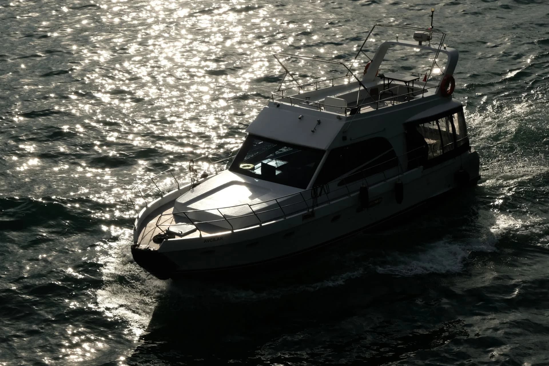A motor yacht crossing sunlit water.