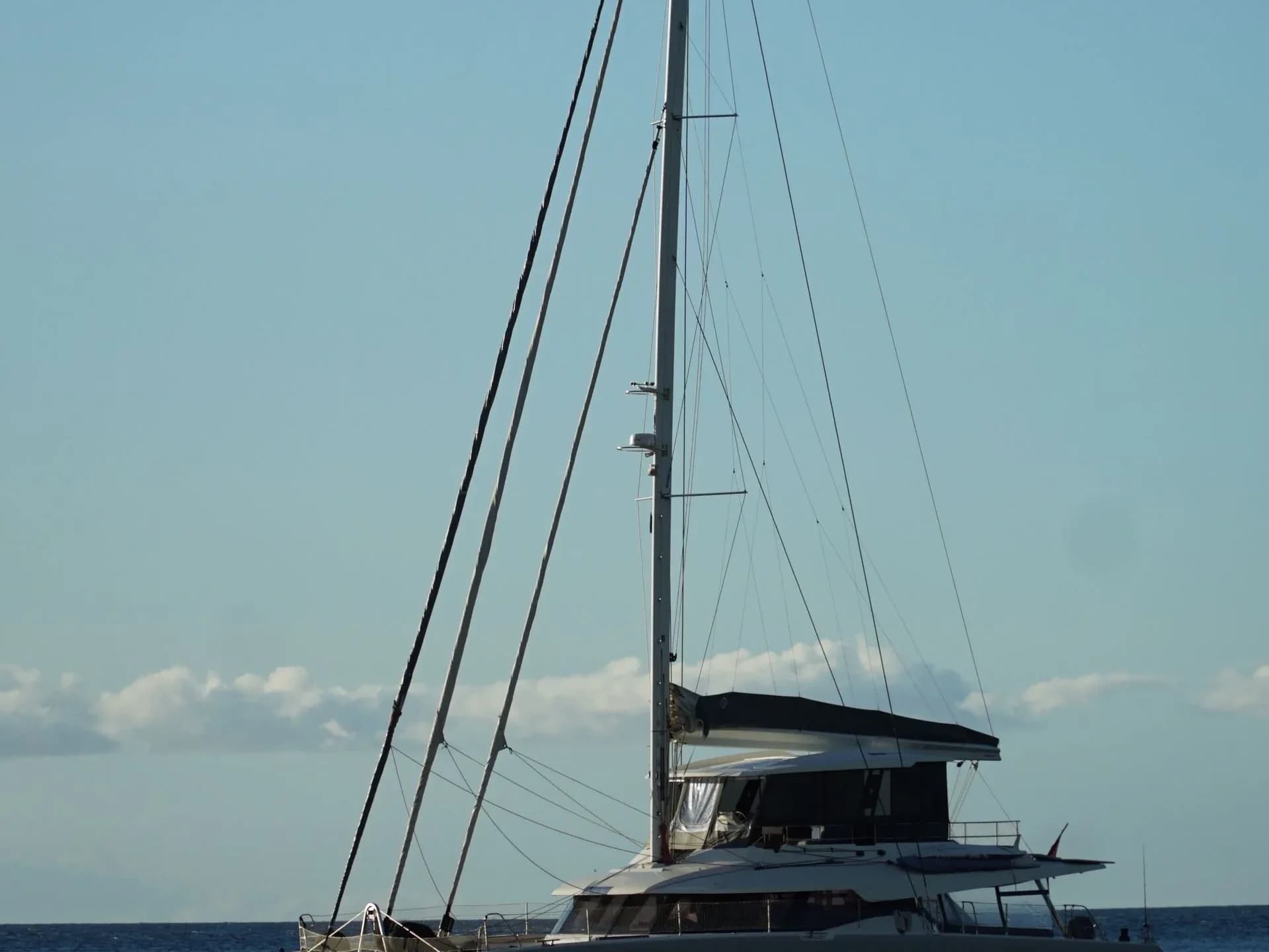 A white catamaran sailing on calm sea water.