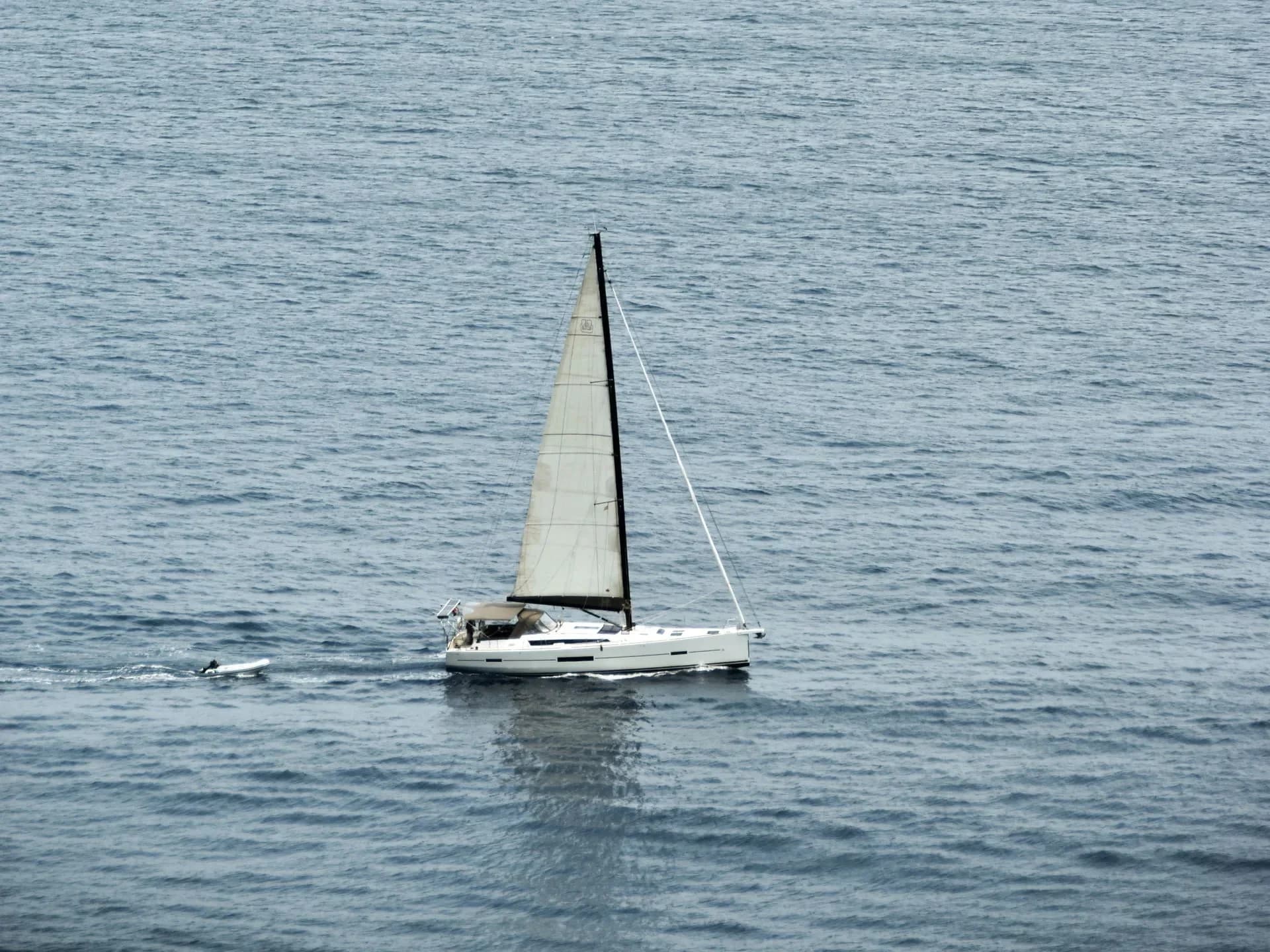 A solitary sailboat on calm sea water.