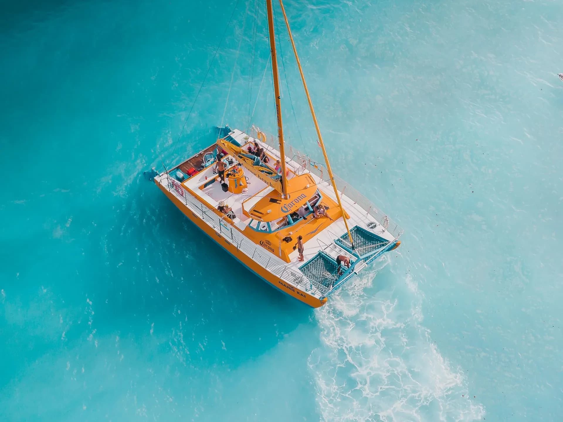 Aerial view of a catamaran with passengers on turquoise water.