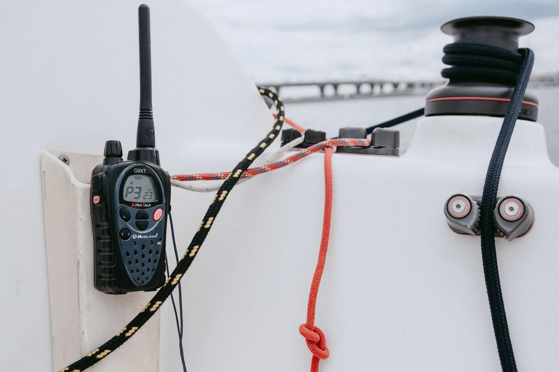 A handheld radio beside ropes and a winch on a yacht.