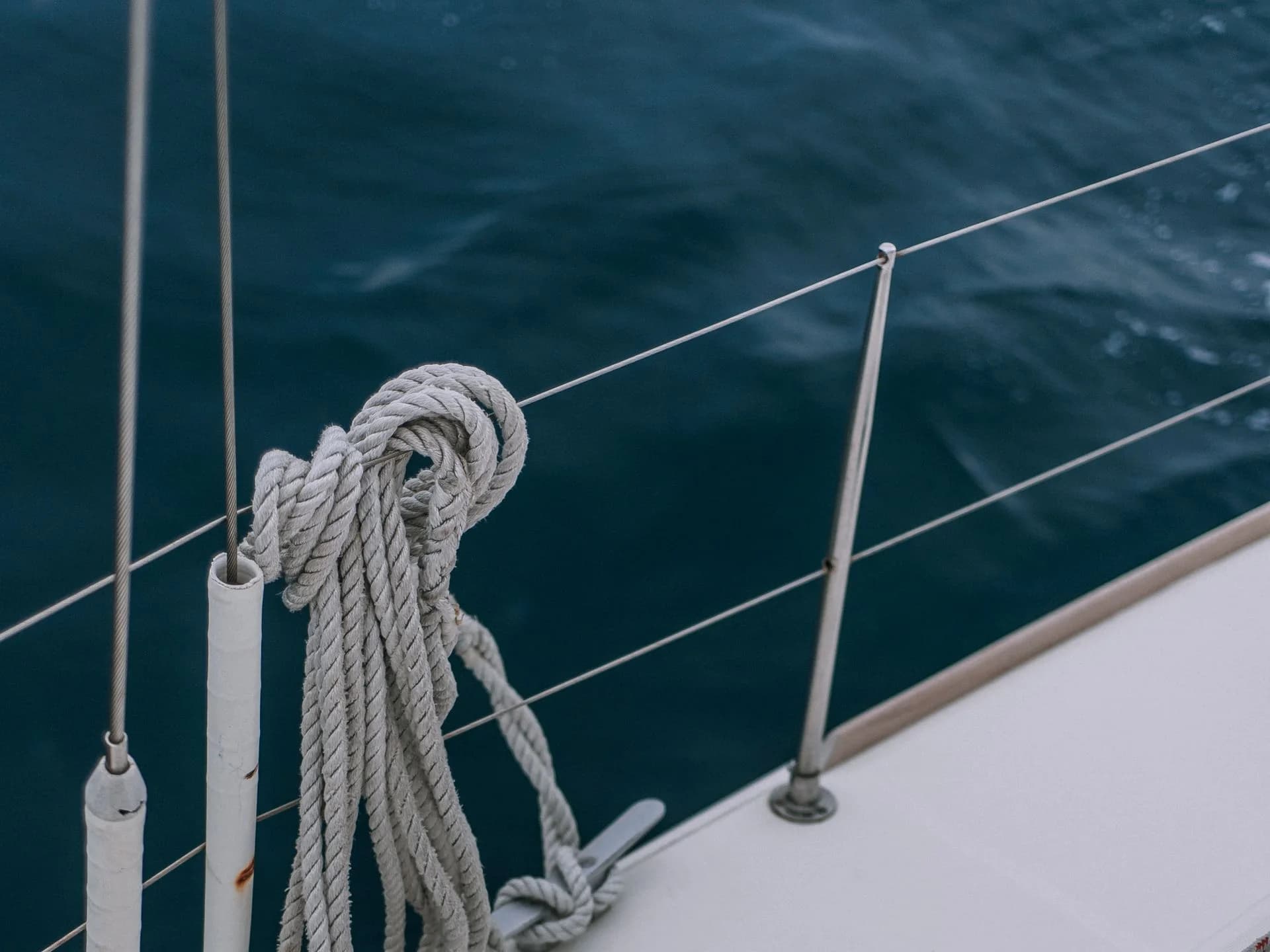 A coiled rope on a yacht railing beside open water.