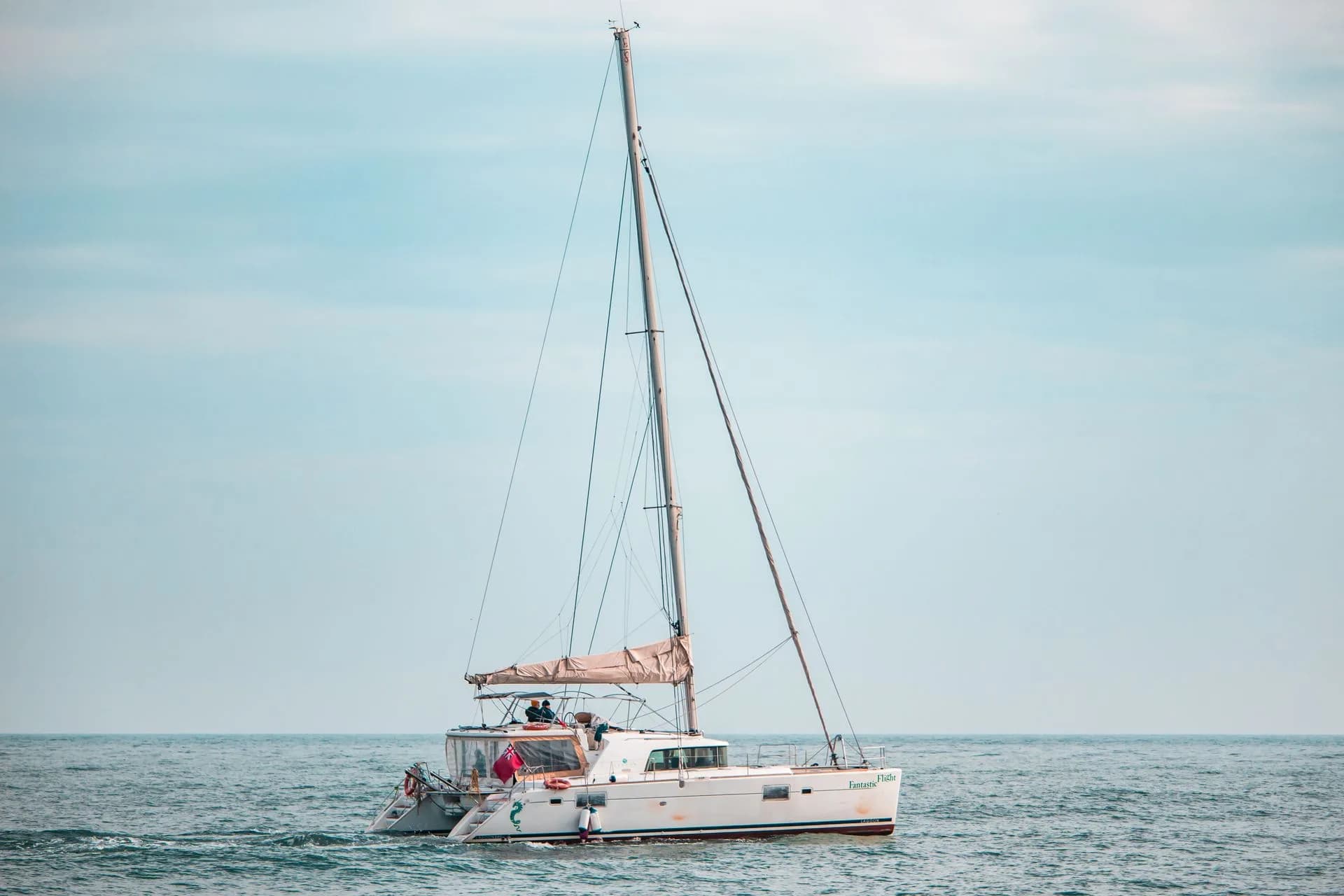 A catamaran on calm water beneath a pastel sky.