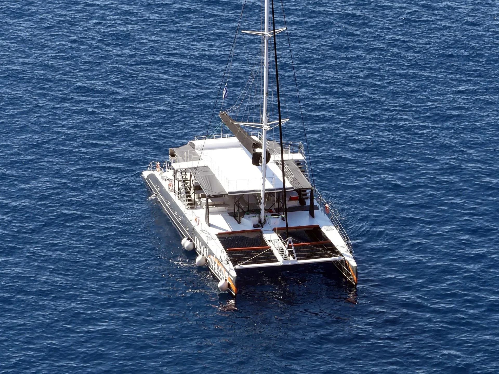 Aerial view of a catamaran sailing on blue water.