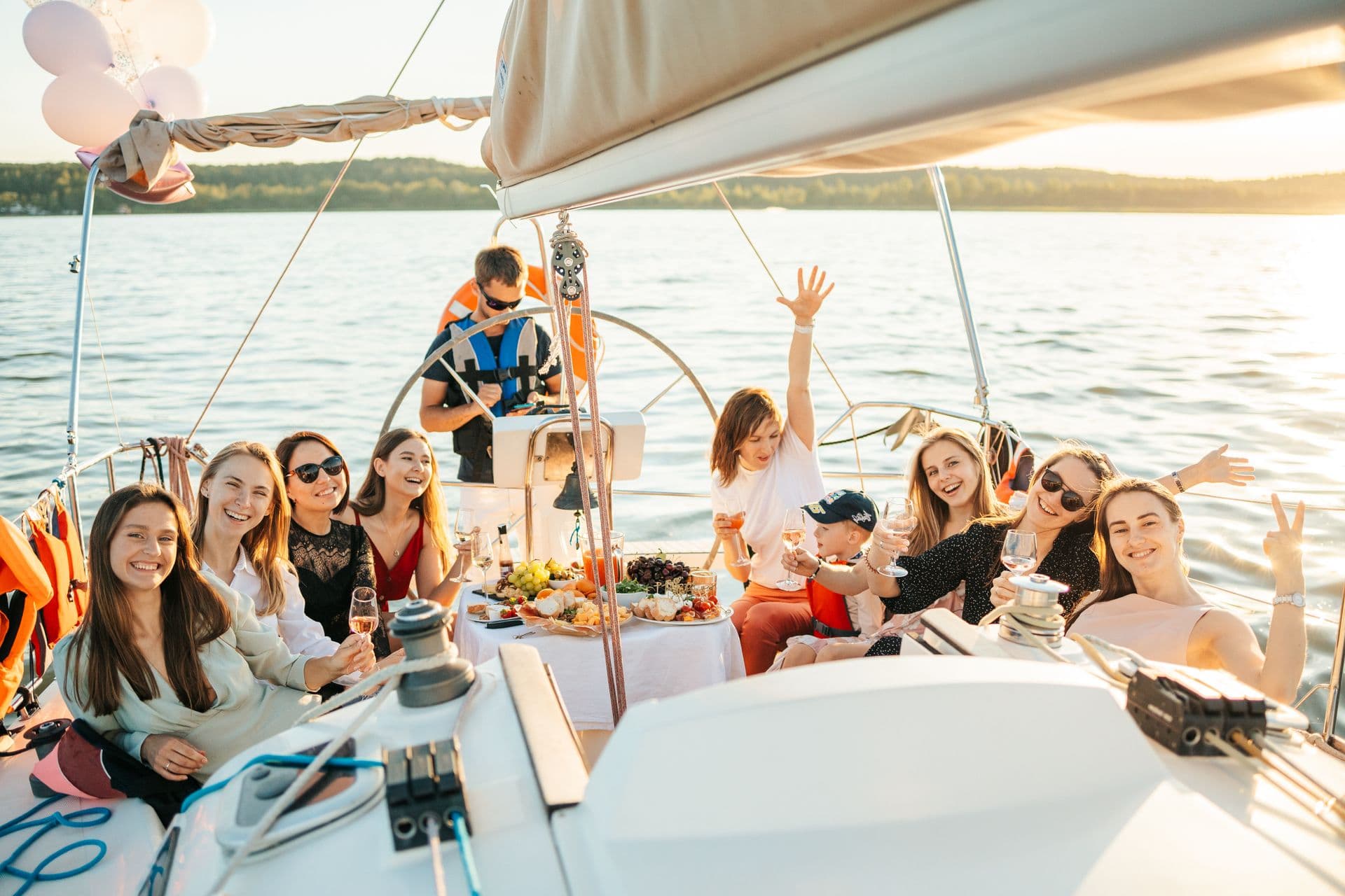 Guests gathered around a sailboat cockpit table in warm evening light